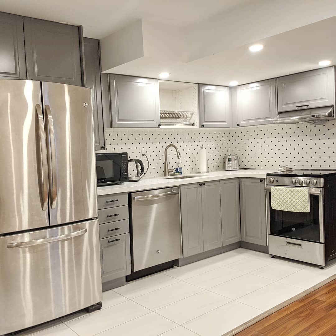 Basement kitchenette after renovation with gray cabinetry and brighter flooring