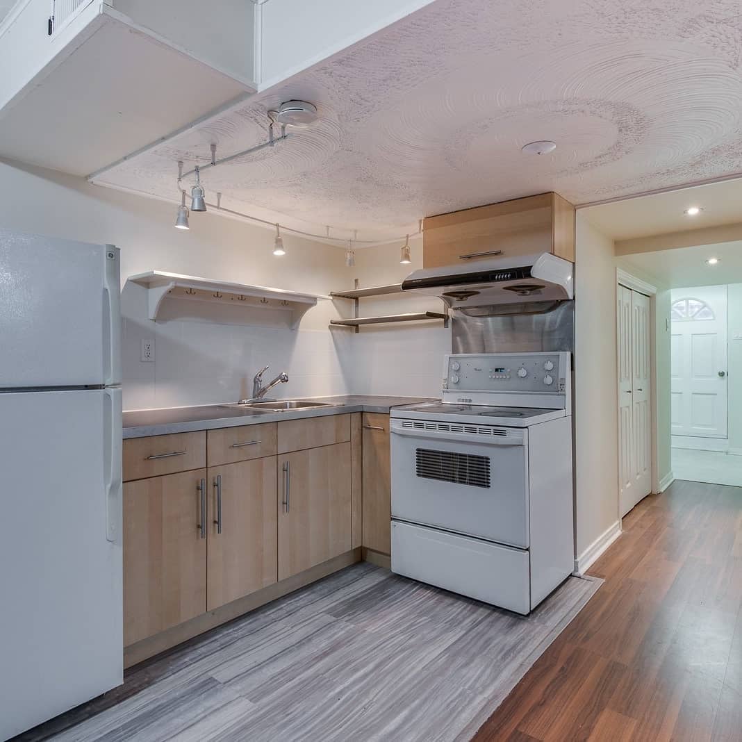 Basement kitchenette before renovation with older cabinets and appliances