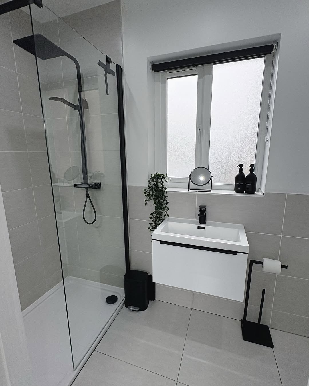 Compact bathroom after renovation with glass shower and black fixtures