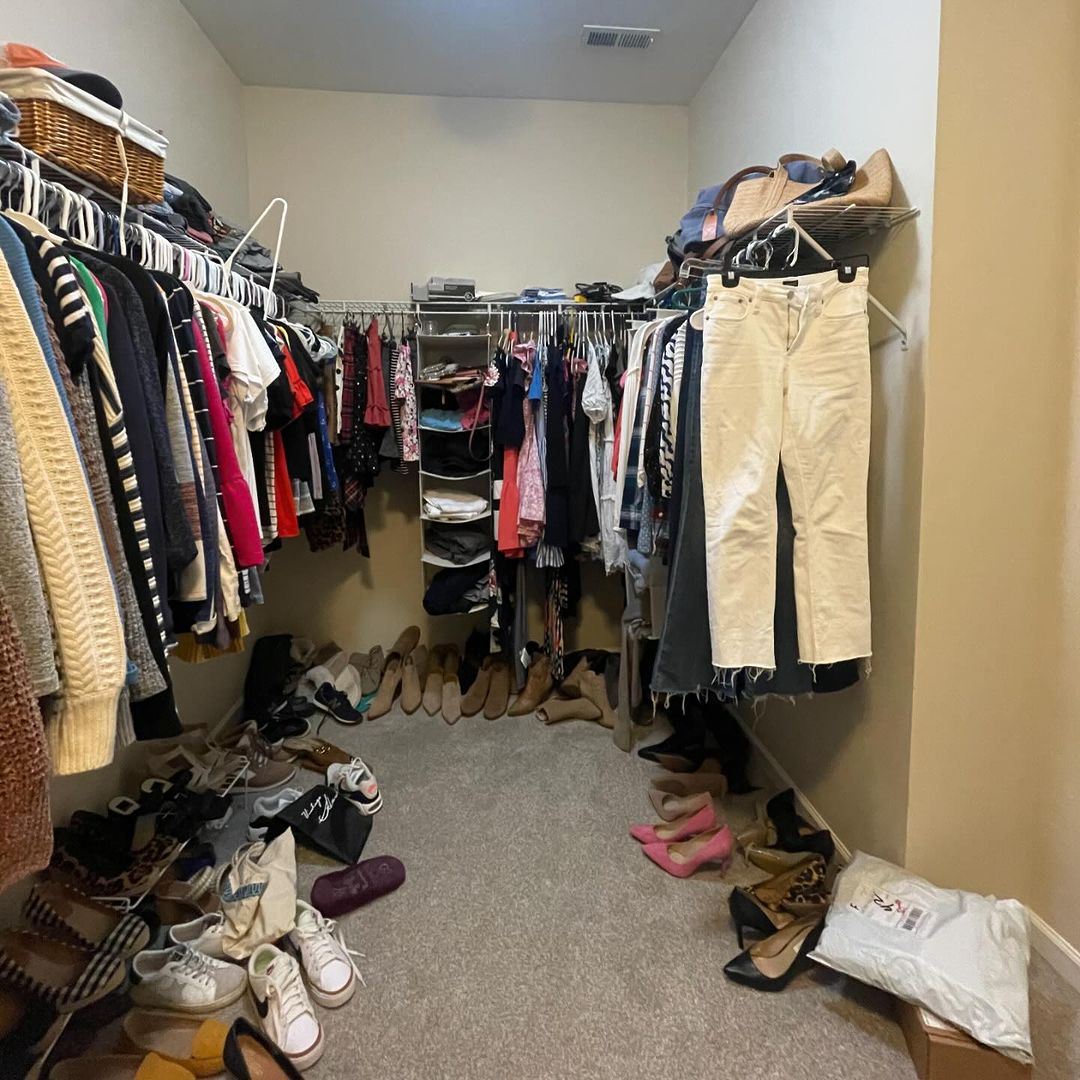Walk-in closet before renovation with open racks and clutter