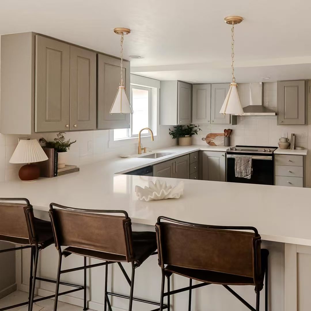 Warm kitchen after renovation with calm cabinetry and pendant lights