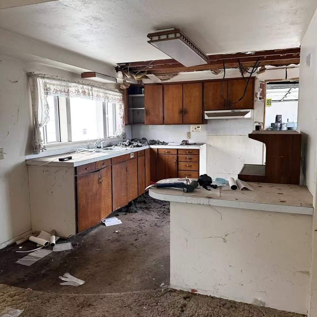 Kitchen before renovation with damaged ceiling and older wood cabinets